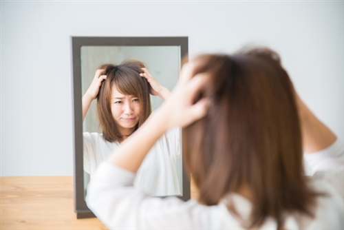 鏡の前で頭抱える女性
